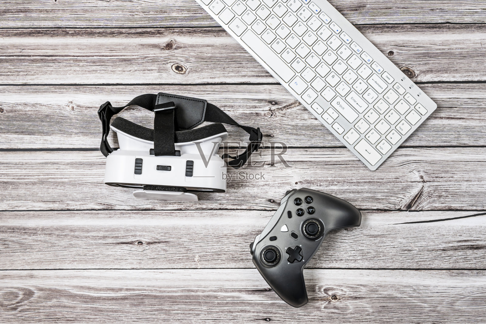 浅色木板桌上的电脑键盘、3D眼镜和游戏手柄照片摄影图片