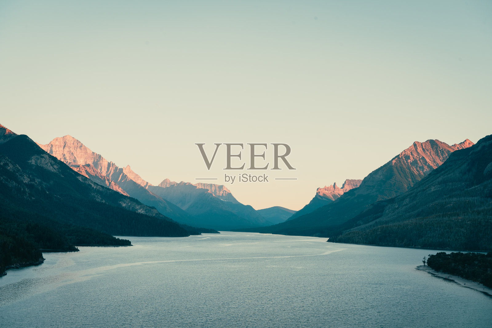 宁静的湖面倒映着雄伟的山峦，天空柔和而宁静。照片摄影图片