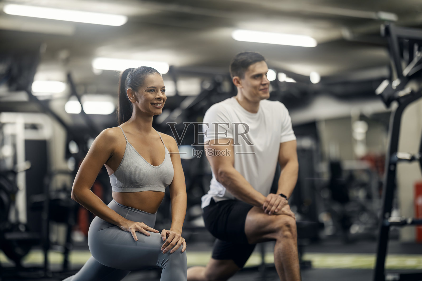 情侣在健身房锻炼时一起拉伸照片摄影图片