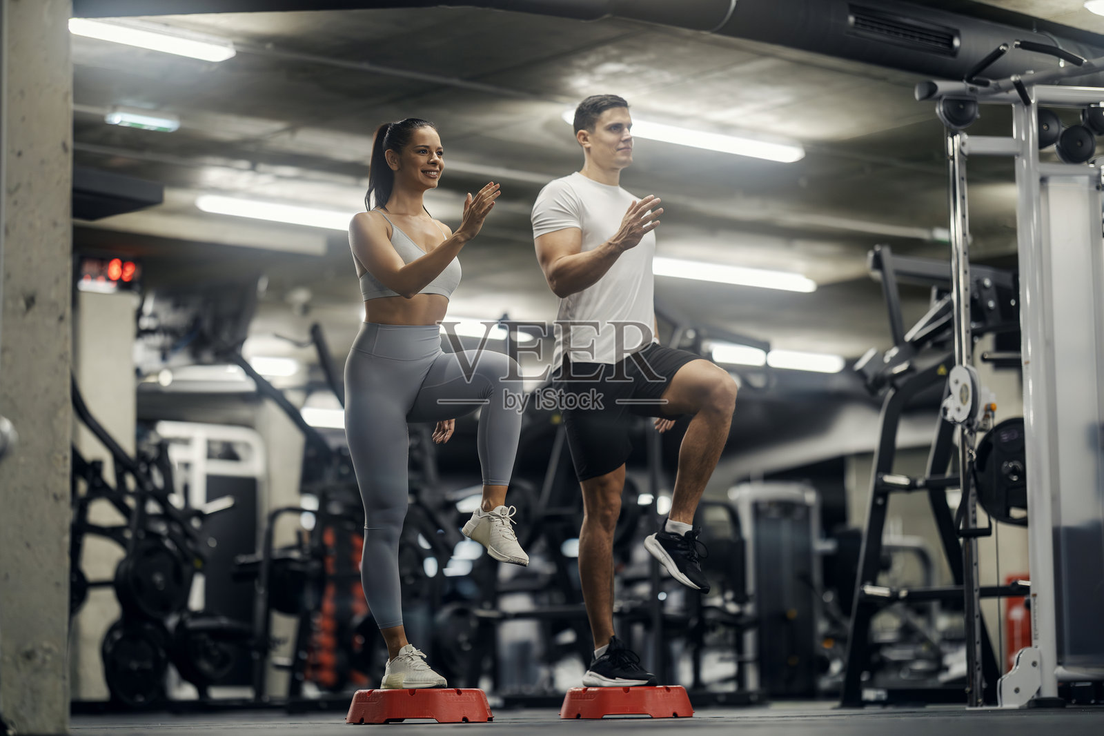 情侣在健身房做高抬腿有氧运动照片摄影图片