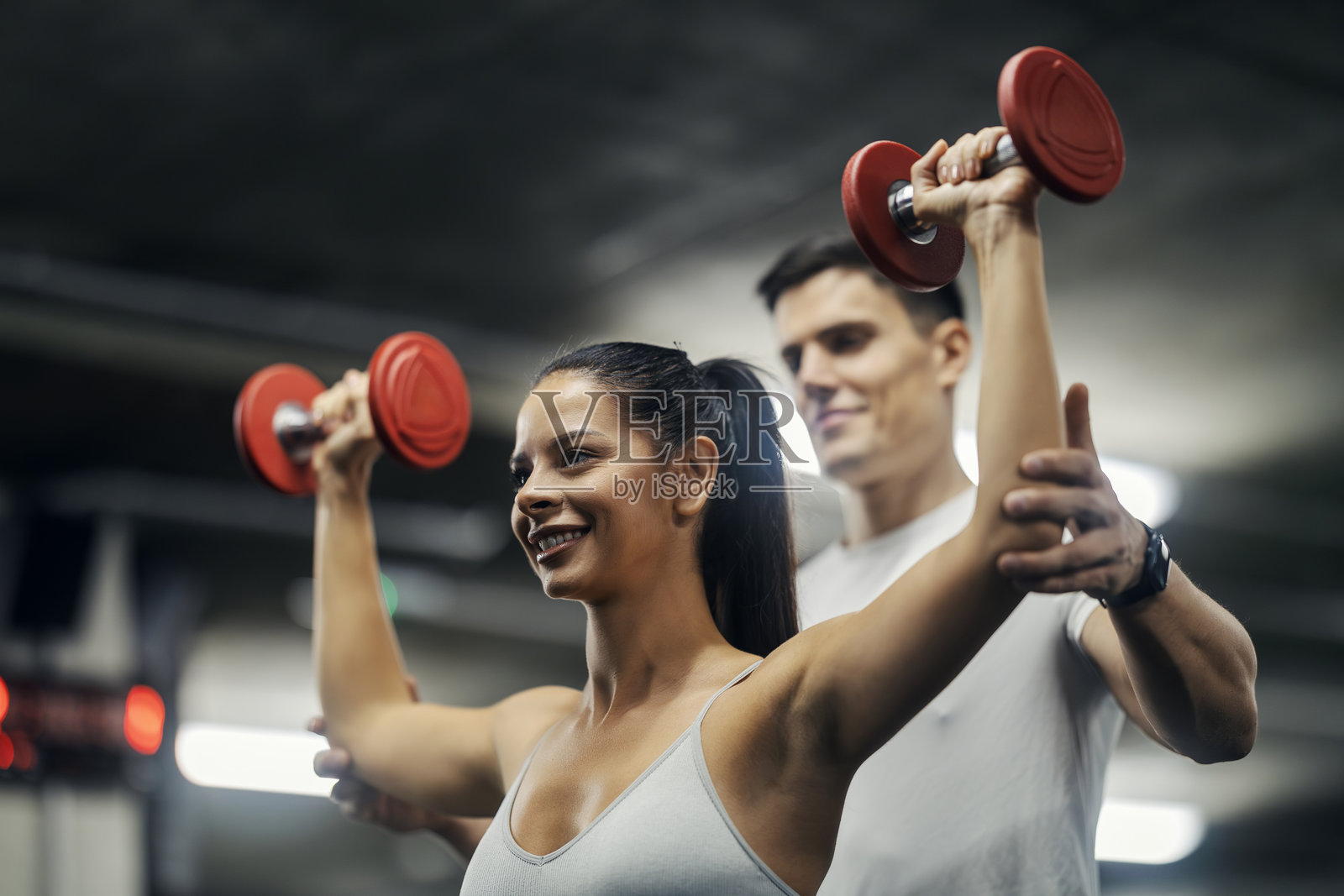 女子在私人教练的指导下进行哑铃训练照片摄影图片