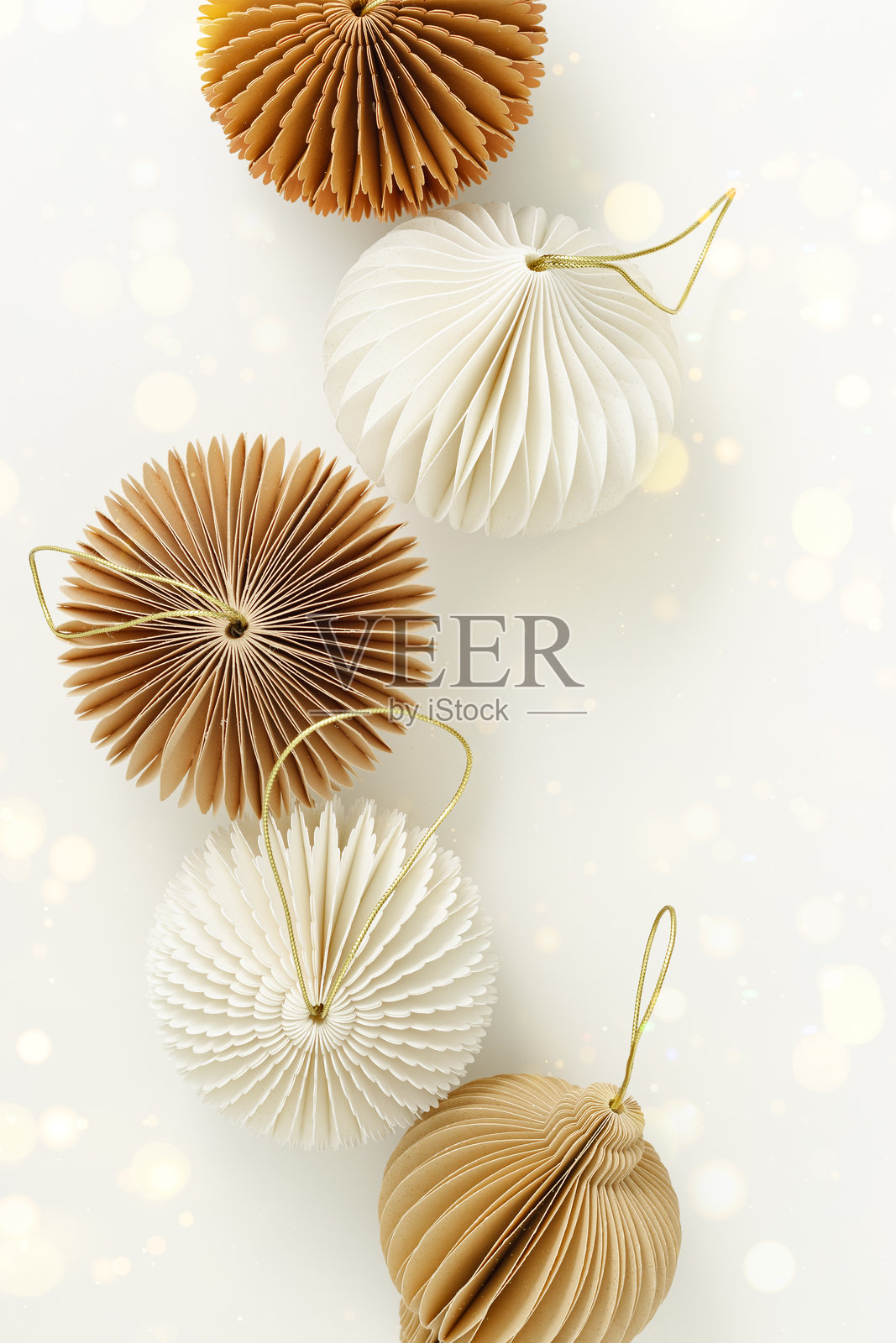 节日时尚纸质圣诞装饰品，米色、棕色，背景为白色，带有金色散景。球体、蜂窝球、手电筒。斯堪的纳维亚节日气氛，创意俯视平铺，可复制空间照片摄影图片
