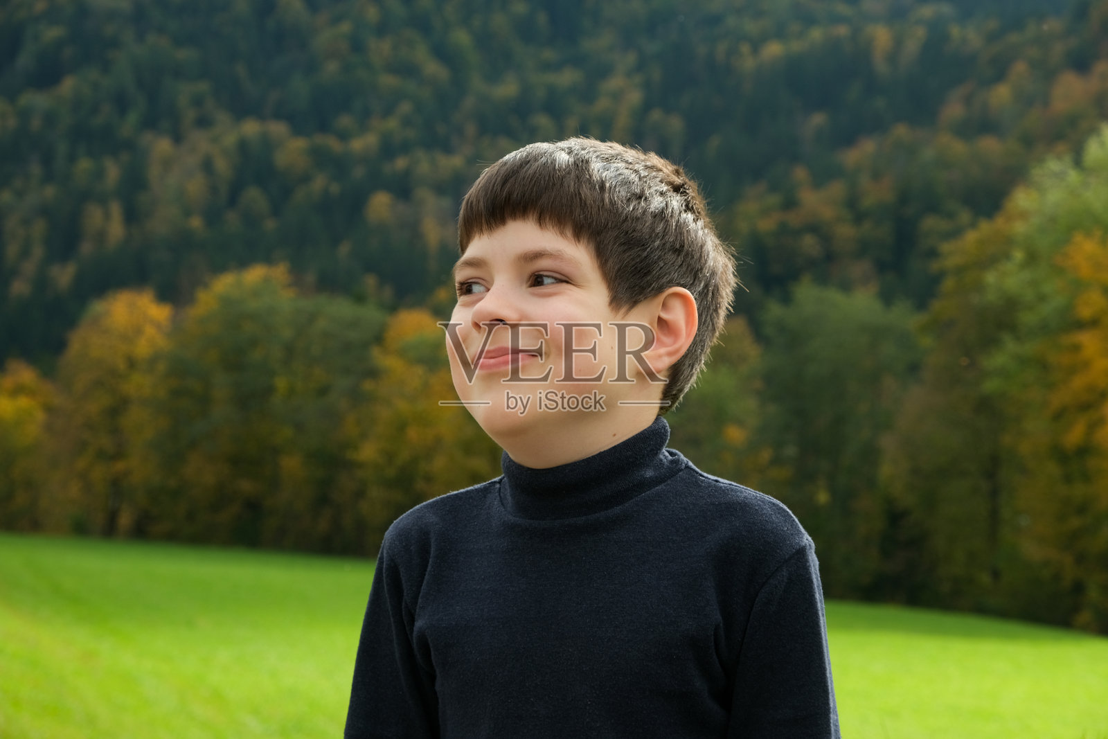 一个8岁的欧洲小男孩，在秋天的自然环境中边走边看向一旁，脸上带着笑容照片摄影图片