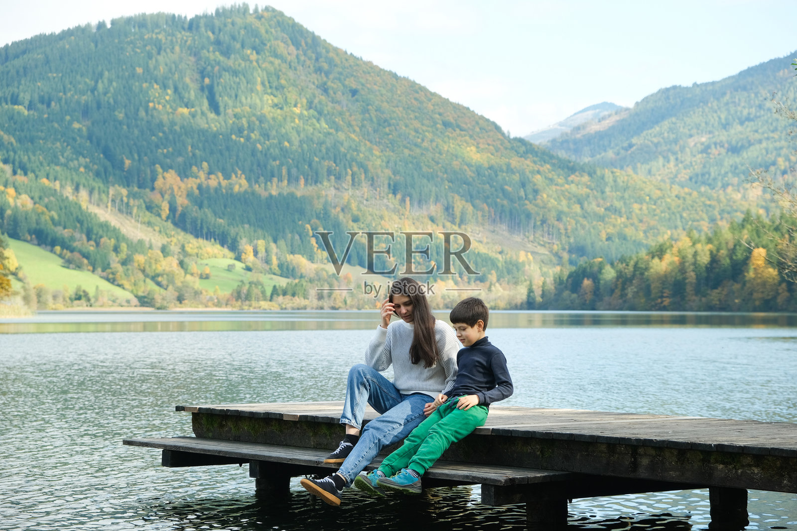 母亲和儿子坐在湖边，在自然环境中交谈和放松照片摄影图片