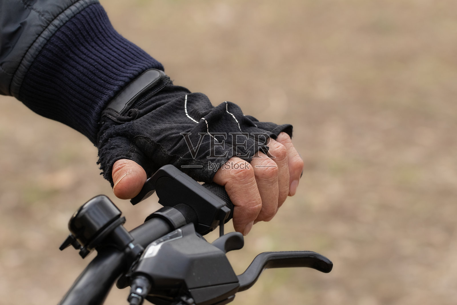 一名穿着保暖夹克的男子骑着自行车。骑行者手部特写。寒冷天气下秋季骑行。照片摄影图片