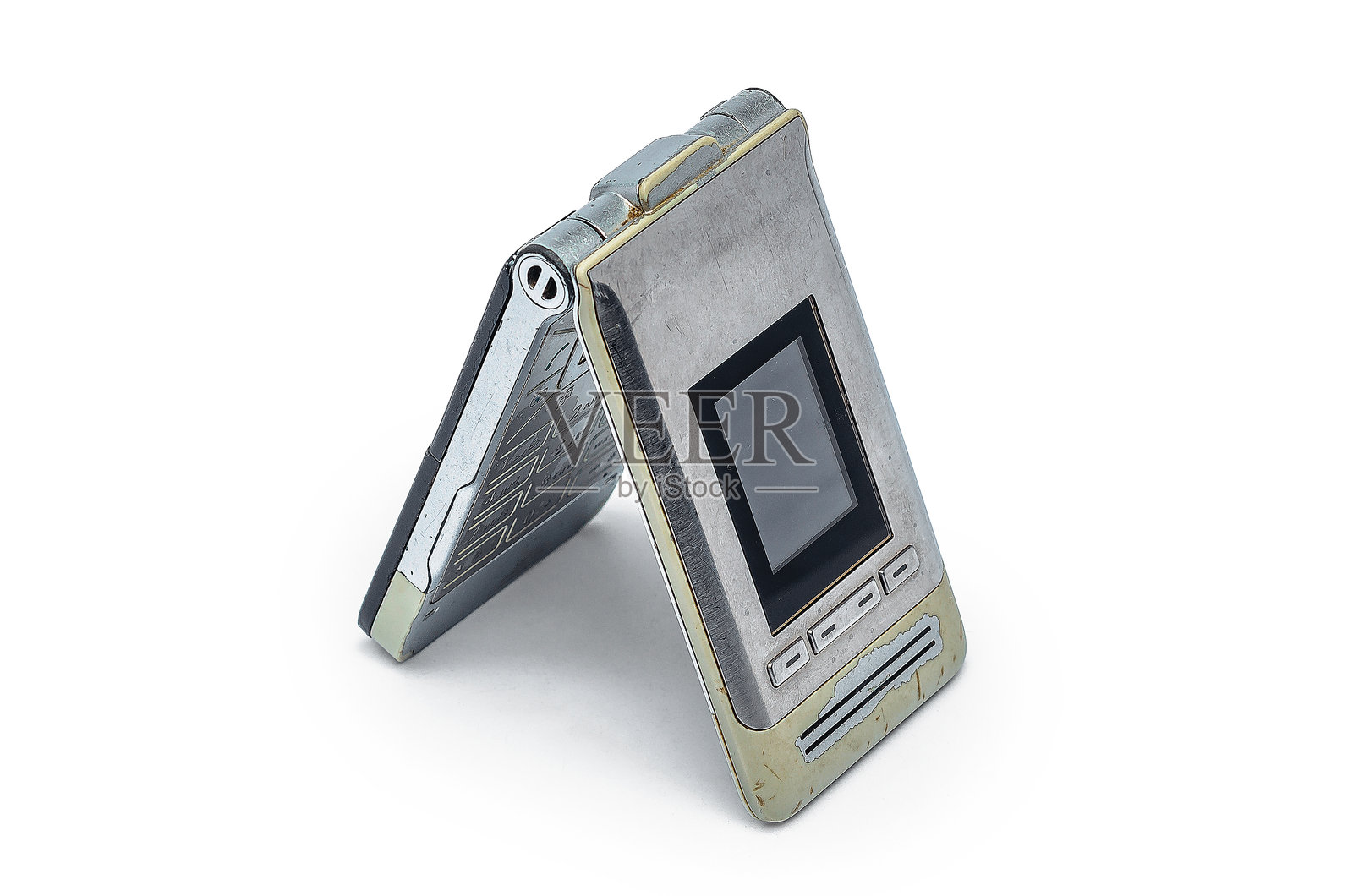 带有磨损机身的复古银色和米色翻盖手机，放在白色背景上照片摄影图片
