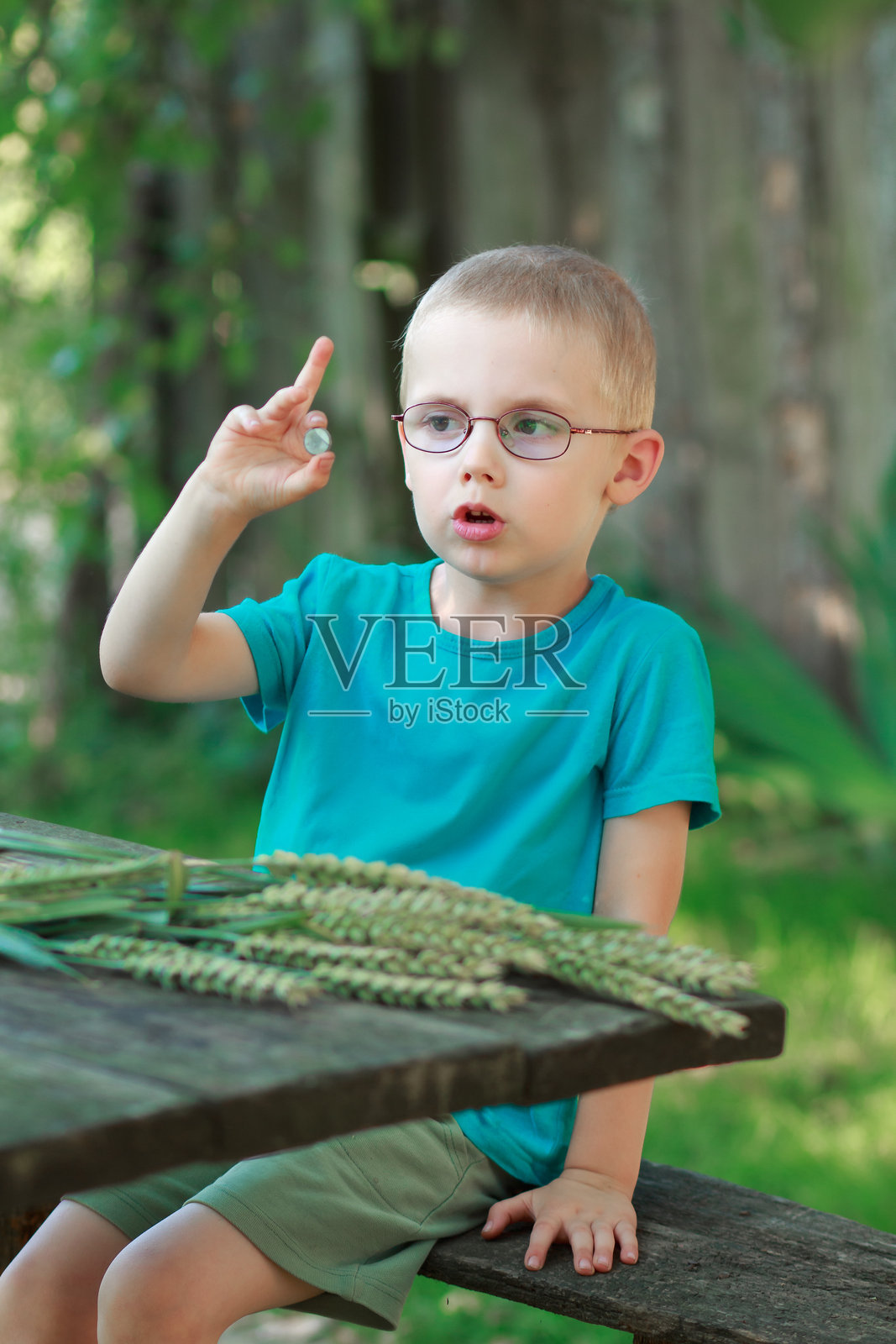 男孩在户外拿着一枚硬币照片摄影图片