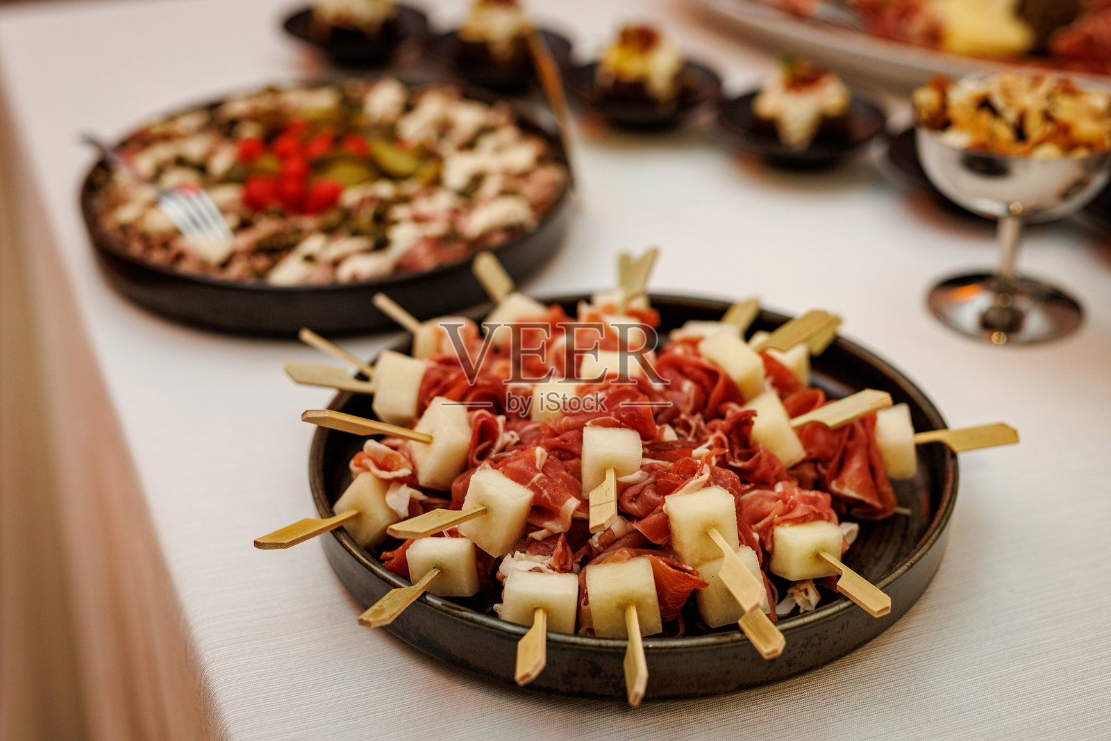 黑盘上的意大利熏火腿蜜瓜串照片摄影图片