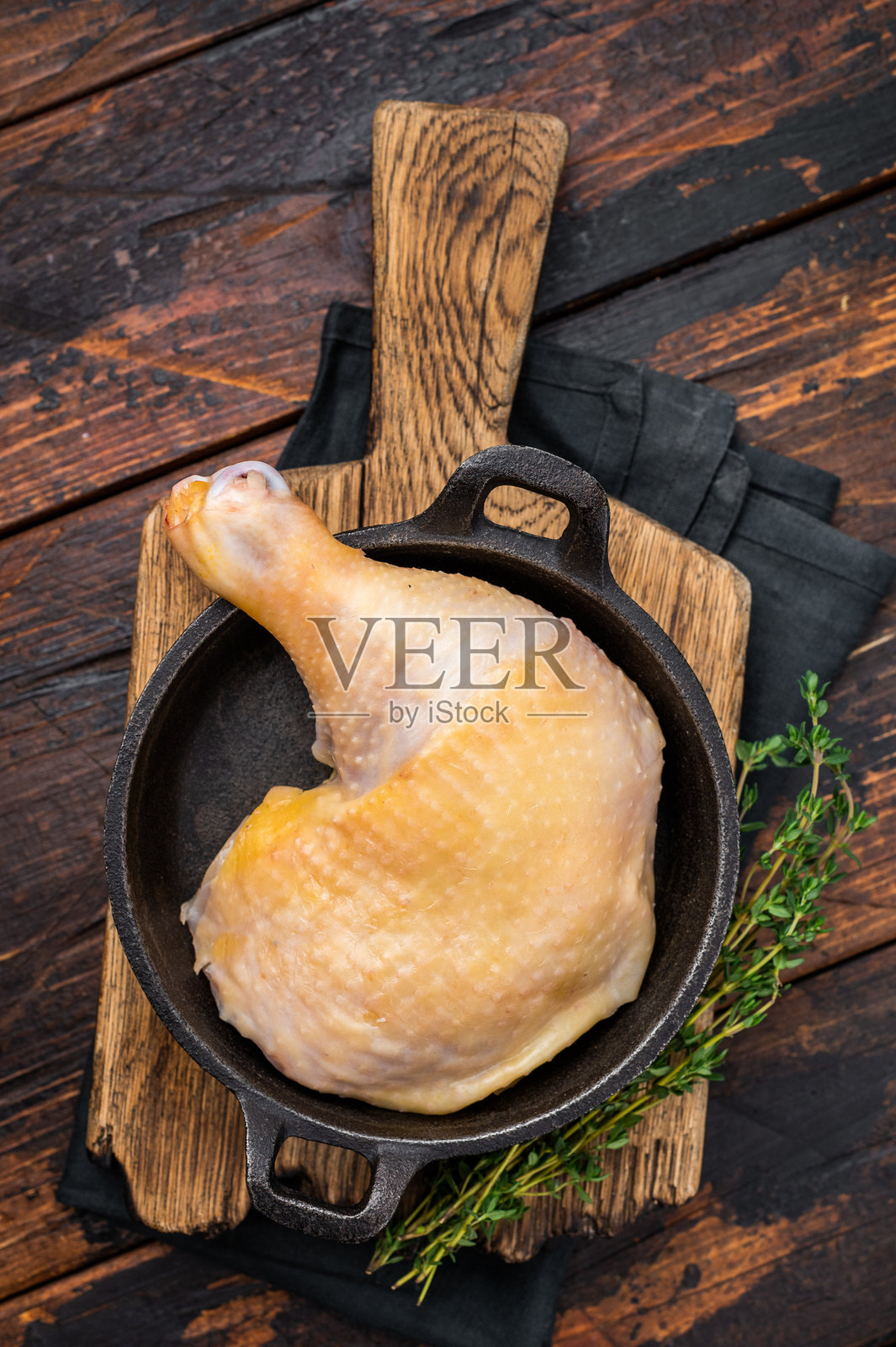 平底锅中准备烹饪的生农场鸡腿，木质背景上的新鲜家禽肉，俯视图。照片摄影图片