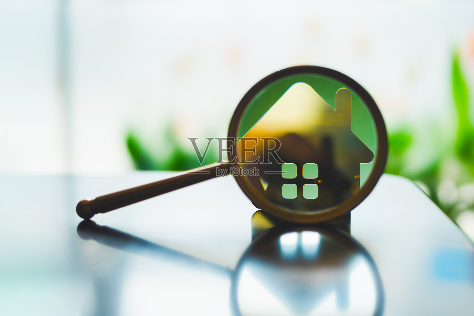 放大镜聚焦房屋图标，象征着物业搜索、房地产分析、房屋搜寻、投资机会、抵押贷款比较和房屋评估的概念。照片摄影图片