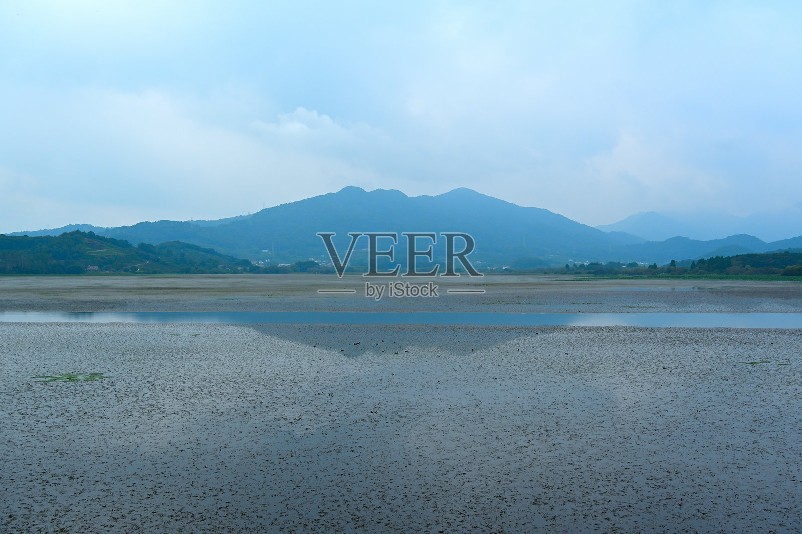 阴天时，远处的山峦倒映在湖水中，景致朦胧照片摄影图片