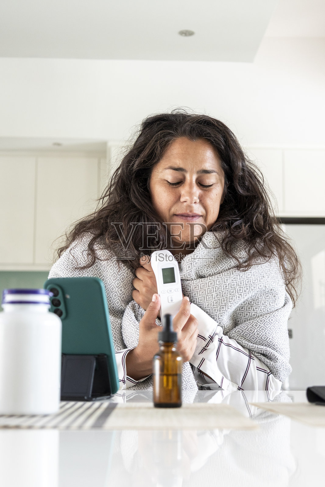 一名女子在家中进行在线医生咨询时测量体温照片摄影图片