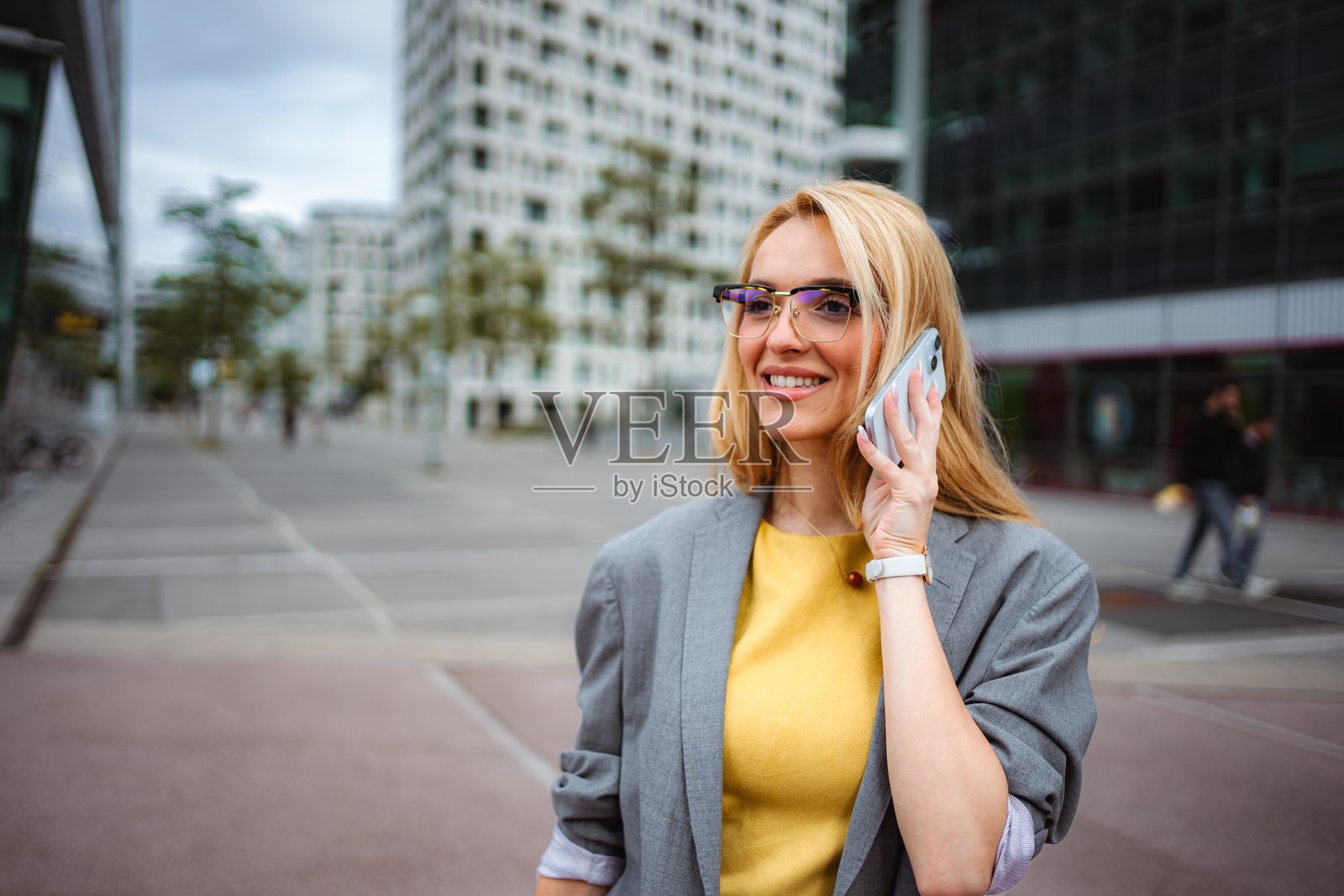 微笑的女商人正在城市中用手机交谈照片摄影图片