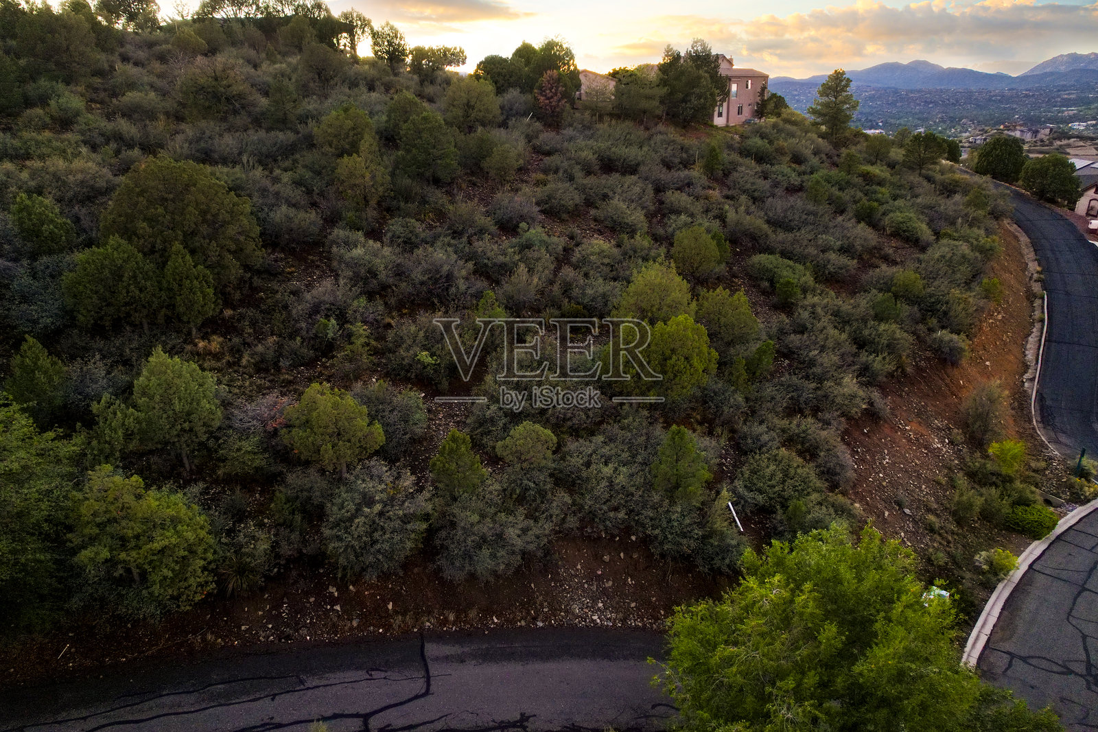 五彩缤纷的傍晚笼罩着荒野，落日余晖洒在布满岩石的地形和远处的树木上。照片摄影图片