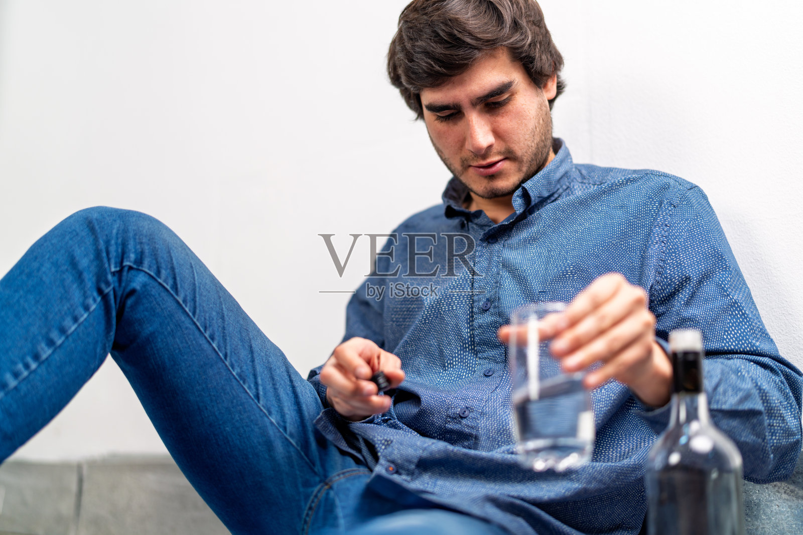 年轻男子在家中手持酒杯，与成瘾作斗争照片摄影图片