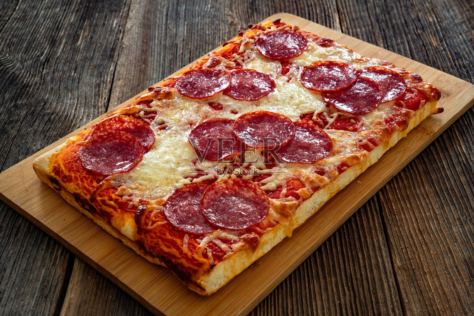 木桌上的意大利辣香肠披萨，配有萨拉米香肠、番茄酱和马苏里拉奶酪照片摄影图片