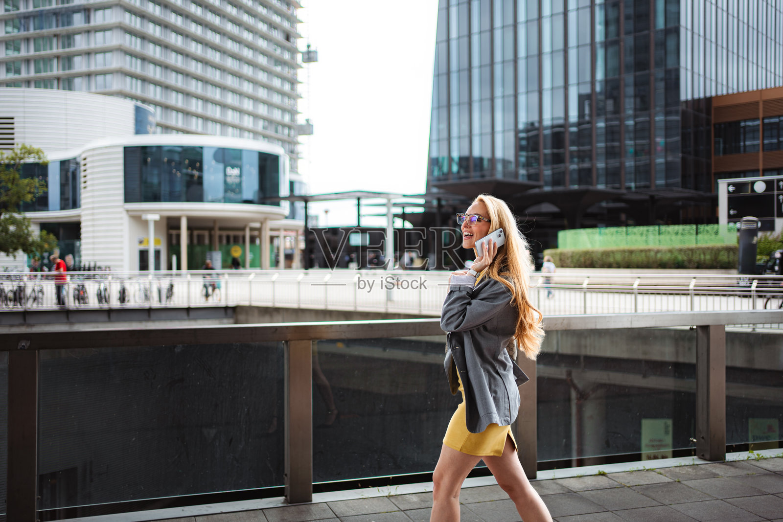 快乐的女商人走在城市街道上，一边打电话照片摄影图片