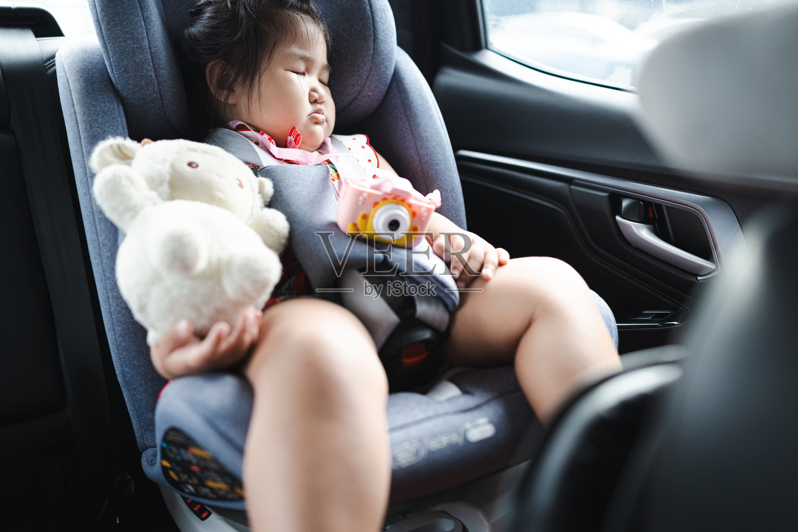 一个可爱的亚洲小女孩在旅行途中，睡在汽车的后座上。照片摄影图片