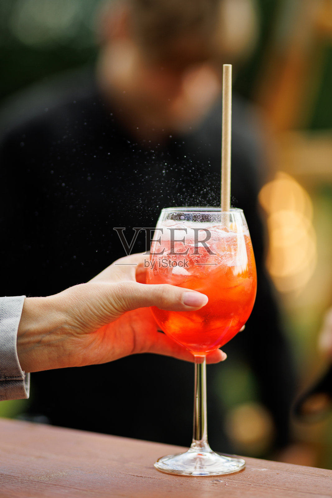 手持一杯加冰的橙味鸡尾酒照片摄影图片
