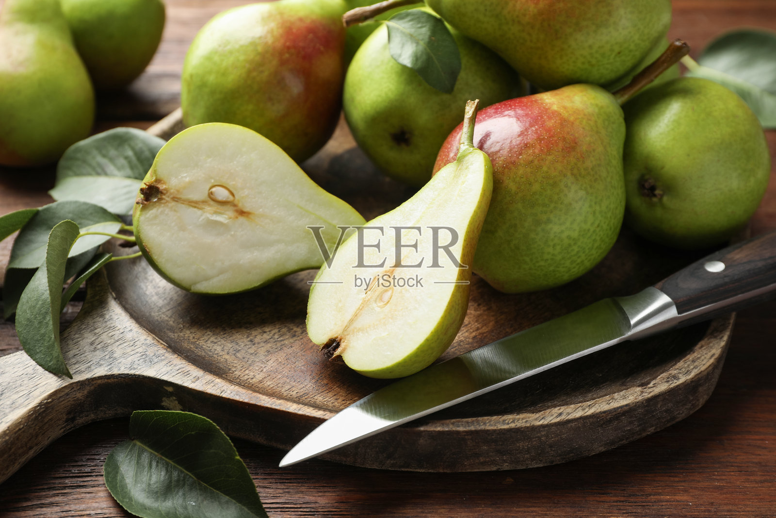 木桌上新鲜的成熟梨子和刀，特写照片摄影图片