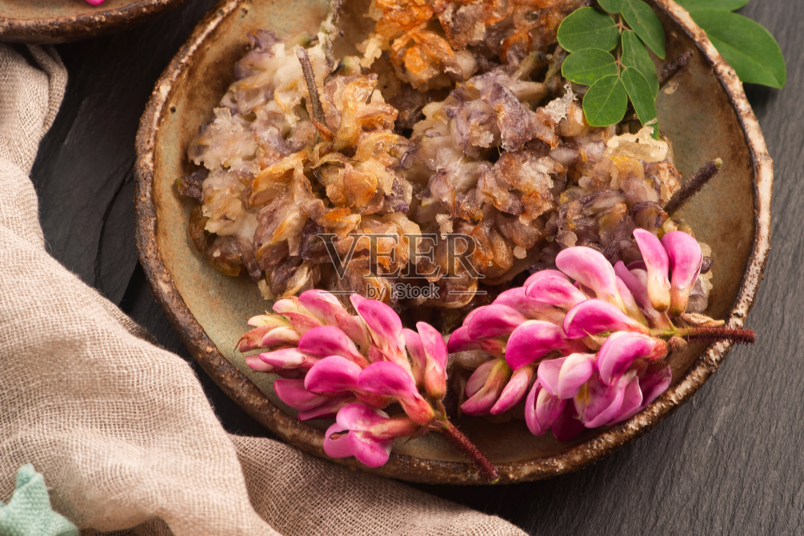 手工陶瓷盘上的粉色金合欢花天妇罗照片摄影图片