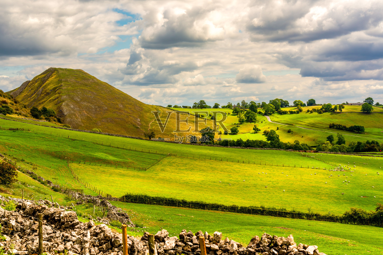 峰区乡村连绵起伏的绿色山丘和草地，天空布满戏剧性的云彩照片摄影图片