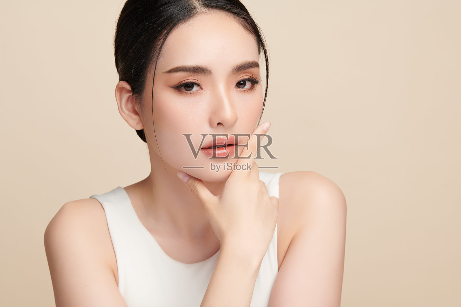 一位美丽的年轻亚洲女性，拥有干净清爽的肌肤，背景为米色。护肤、面部护理、美容学、美妆和水疗。一位亚洲女性的优雅肖像。照片摄影图片