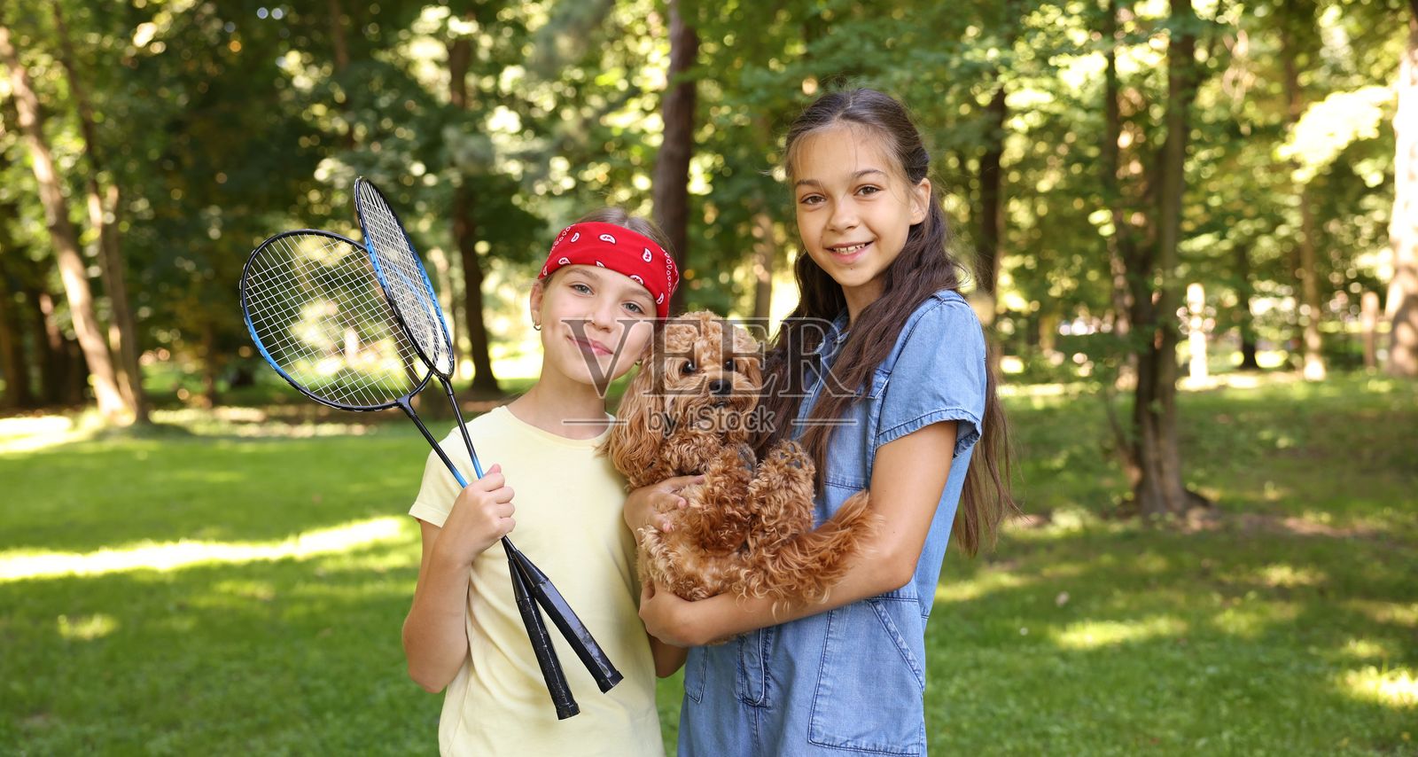 可爱小女孩们在公园里，带着羽毛球拍和狗狗的肖像照照片摄影图片