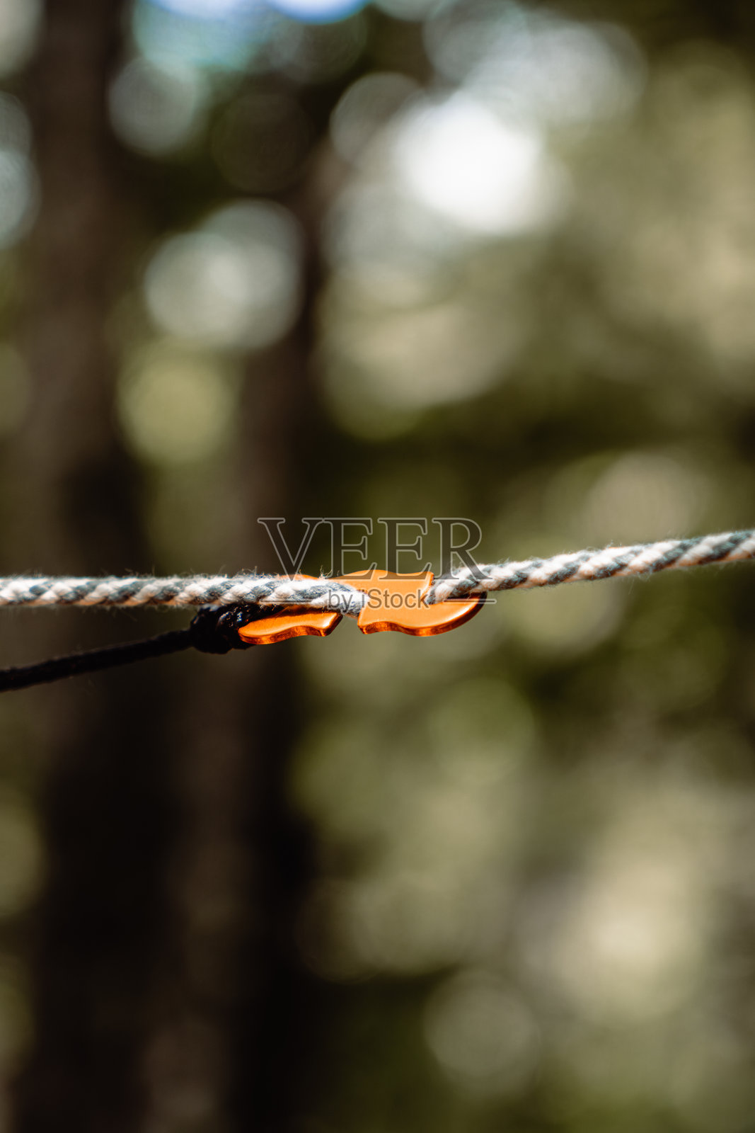 一根黑白伞绳上橙色绳索调节器（张紧器）的垂直微距镜头照片摄影图片