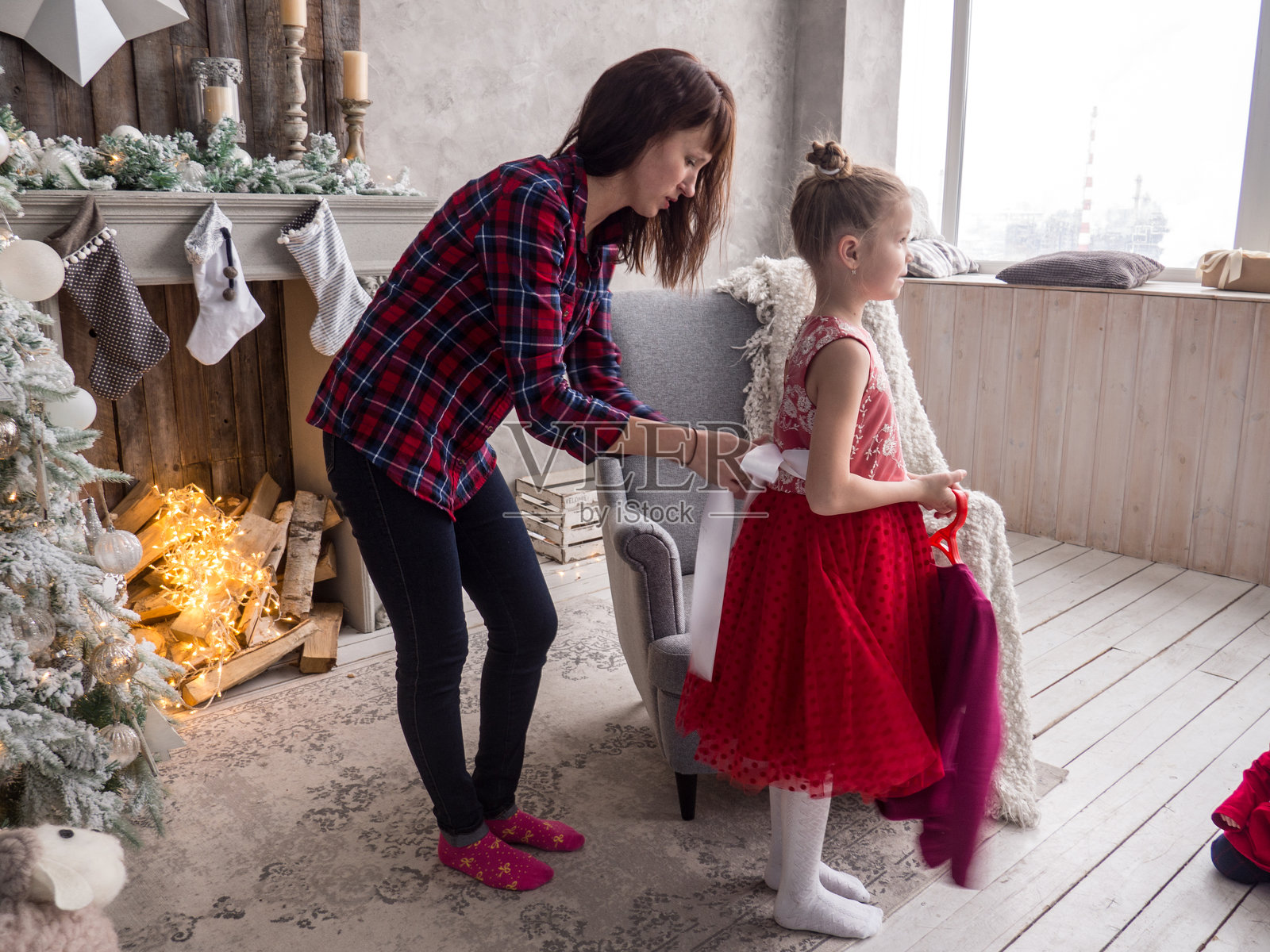 圣诞节准备：妈妈帮女儿穿上红色礼服，准备参加圣诞舞会。照片摄影图片