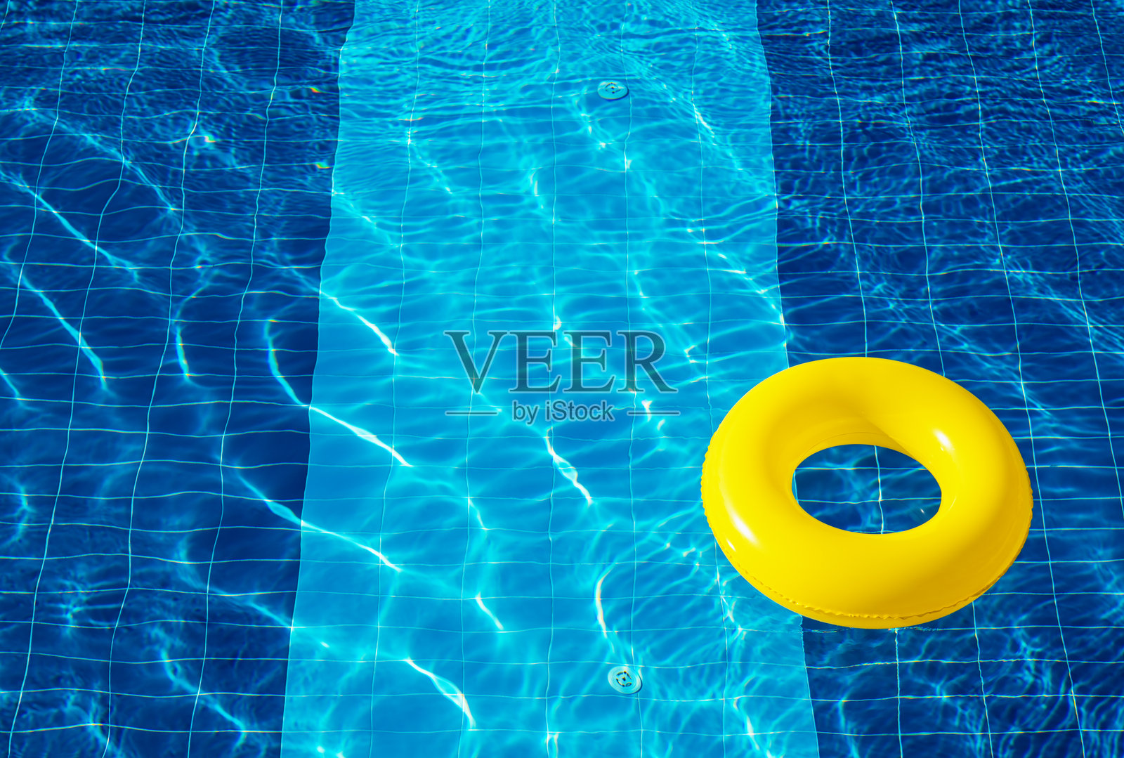 黄色的泳圈，漂浮在清爽的蓝色泳池中照片摄影图片