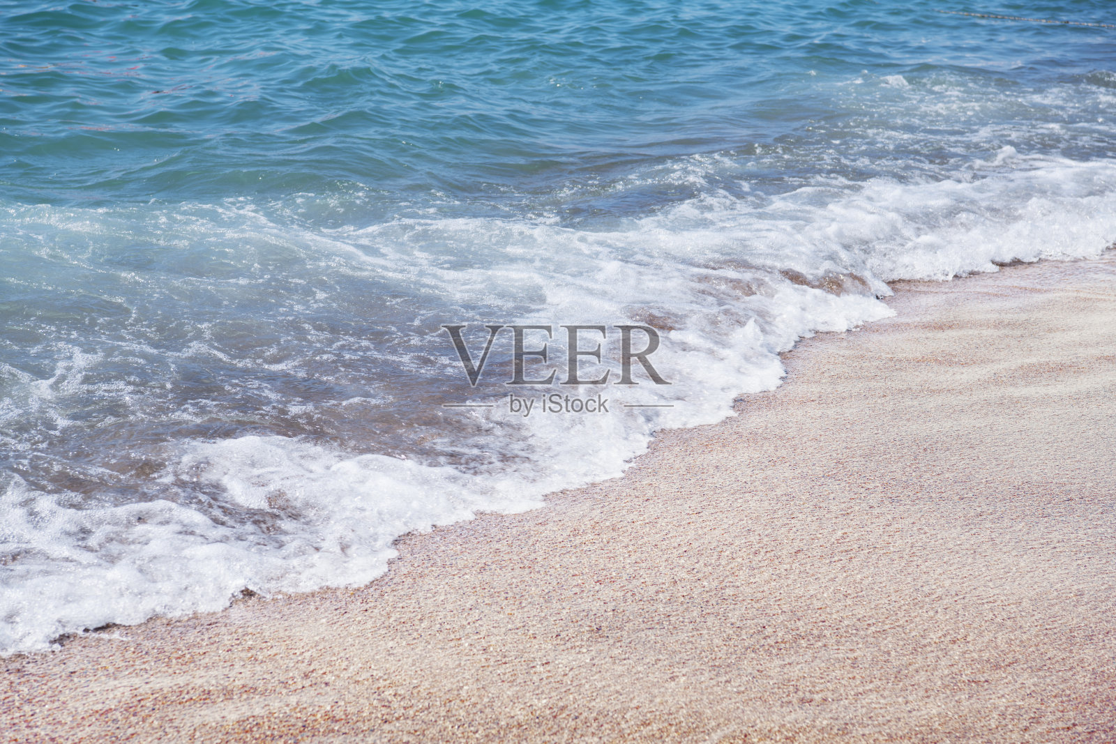 柔软的蓝色海浪拍打在沙滩上。照片摄影图片