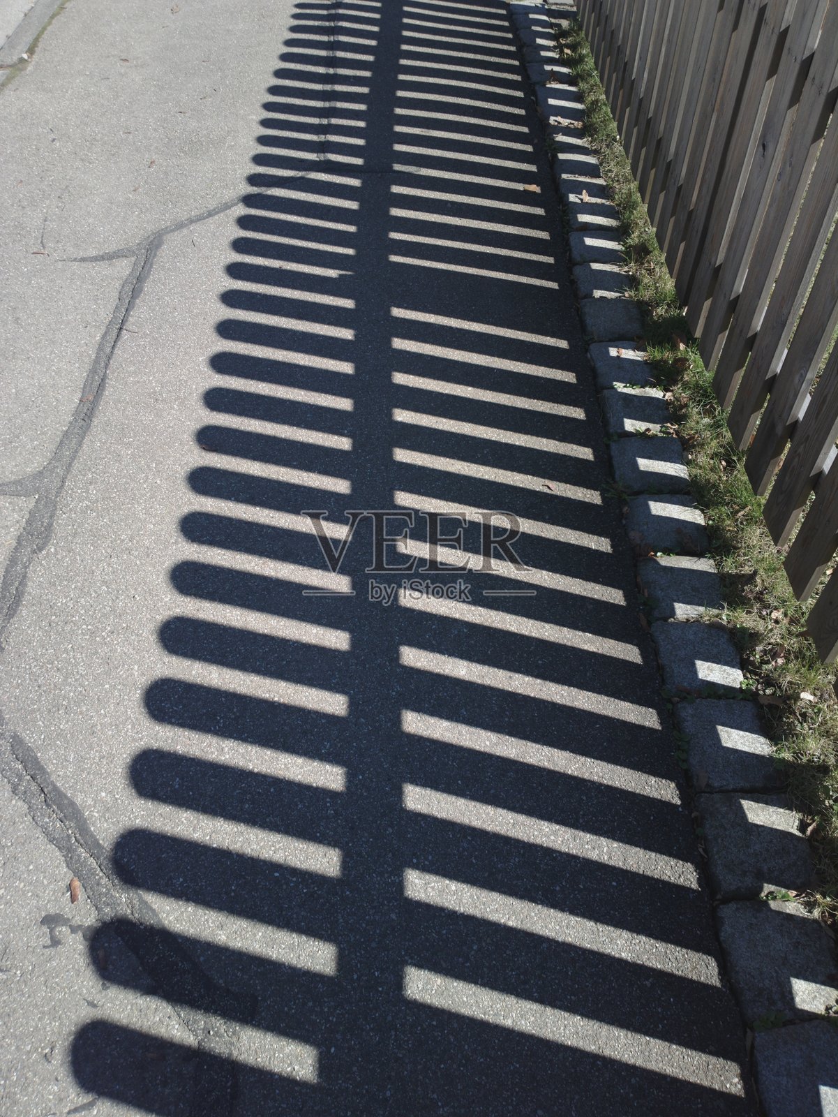 栅栏的影子投射在人行道上照片摄影图片