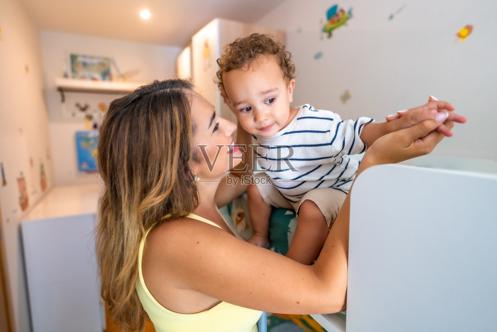 母亲在儿童卧室里抱着她的小儿子照片摄影图片