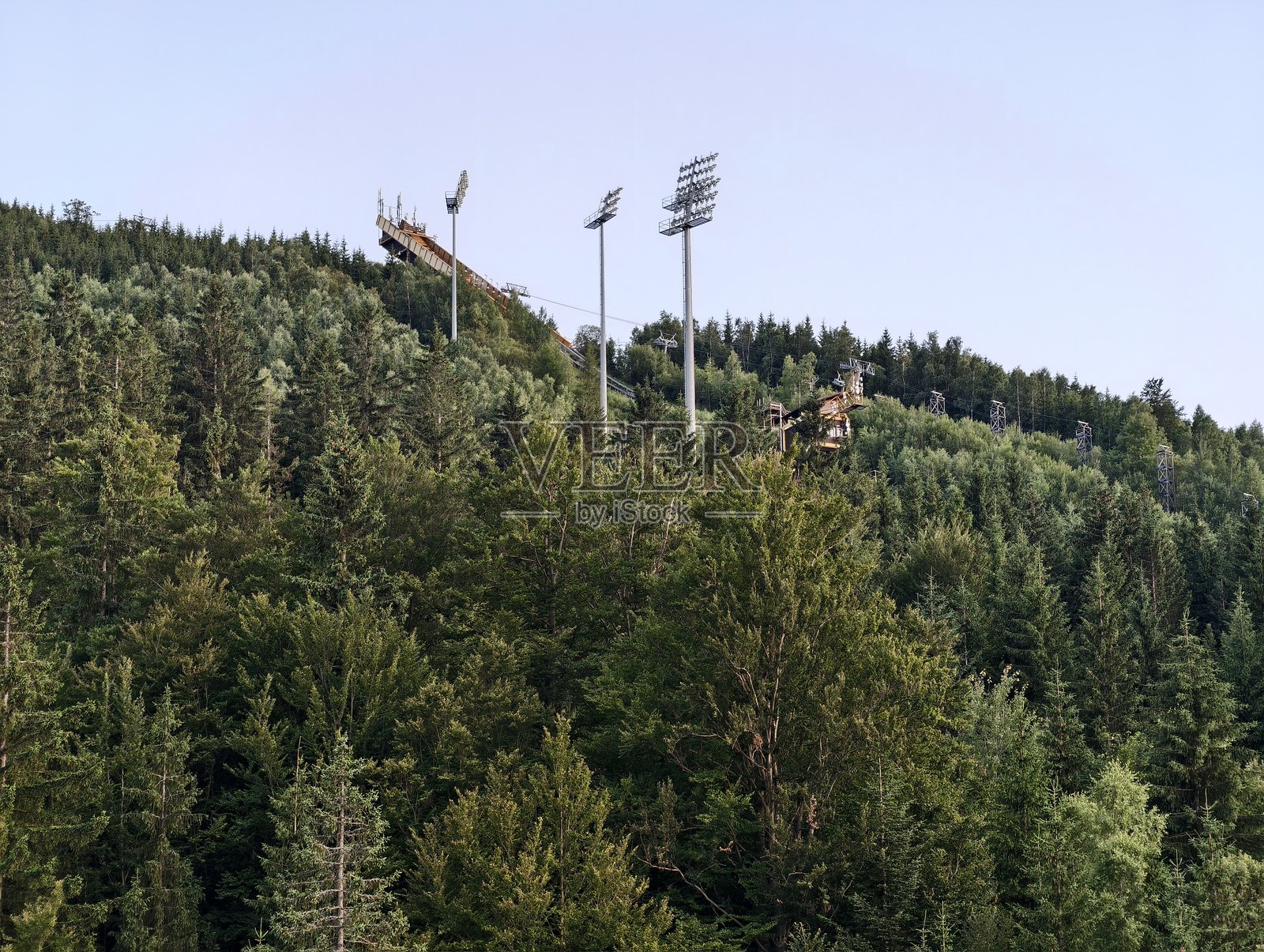 灯光与自然形成对比，体育场灯光与崎岖山脉交织的戏剧性场景照片摄影图片