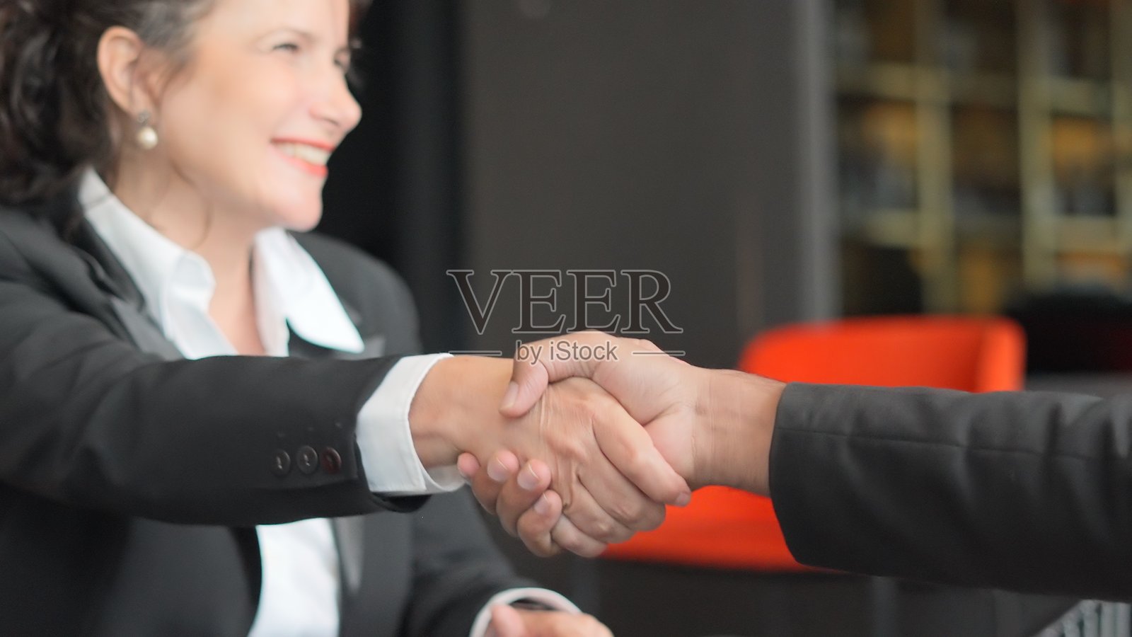 一群专业的男商人和女商人聚集在现代会议室，在就合作策略、新投资和财务发展计划达成一致后握手。他们的团队合作强调了协作、创新、照片摄影图片