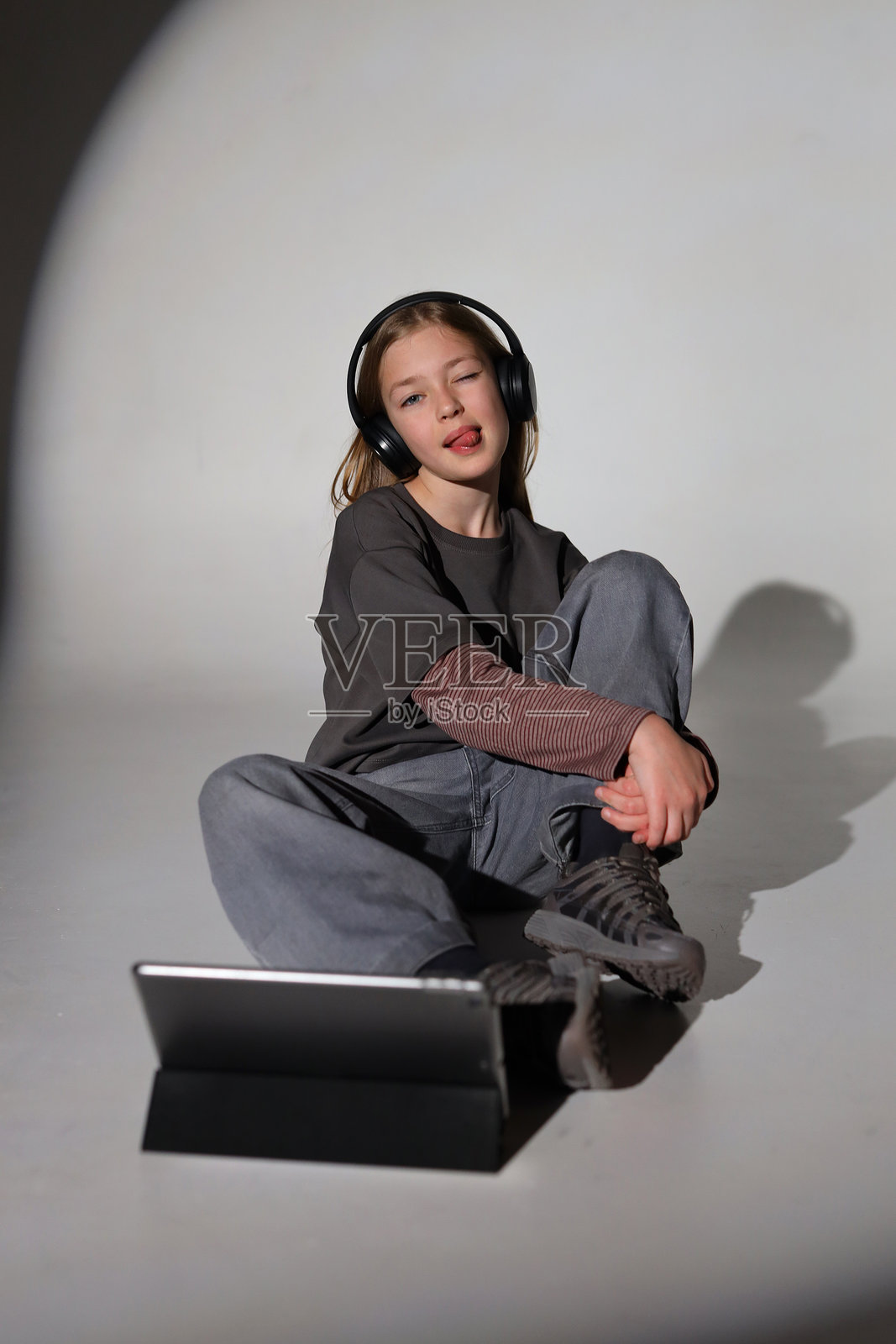 穿着休闲服的白人小女孩戴着耳机，放松地使用平板电脑照片摄影图片