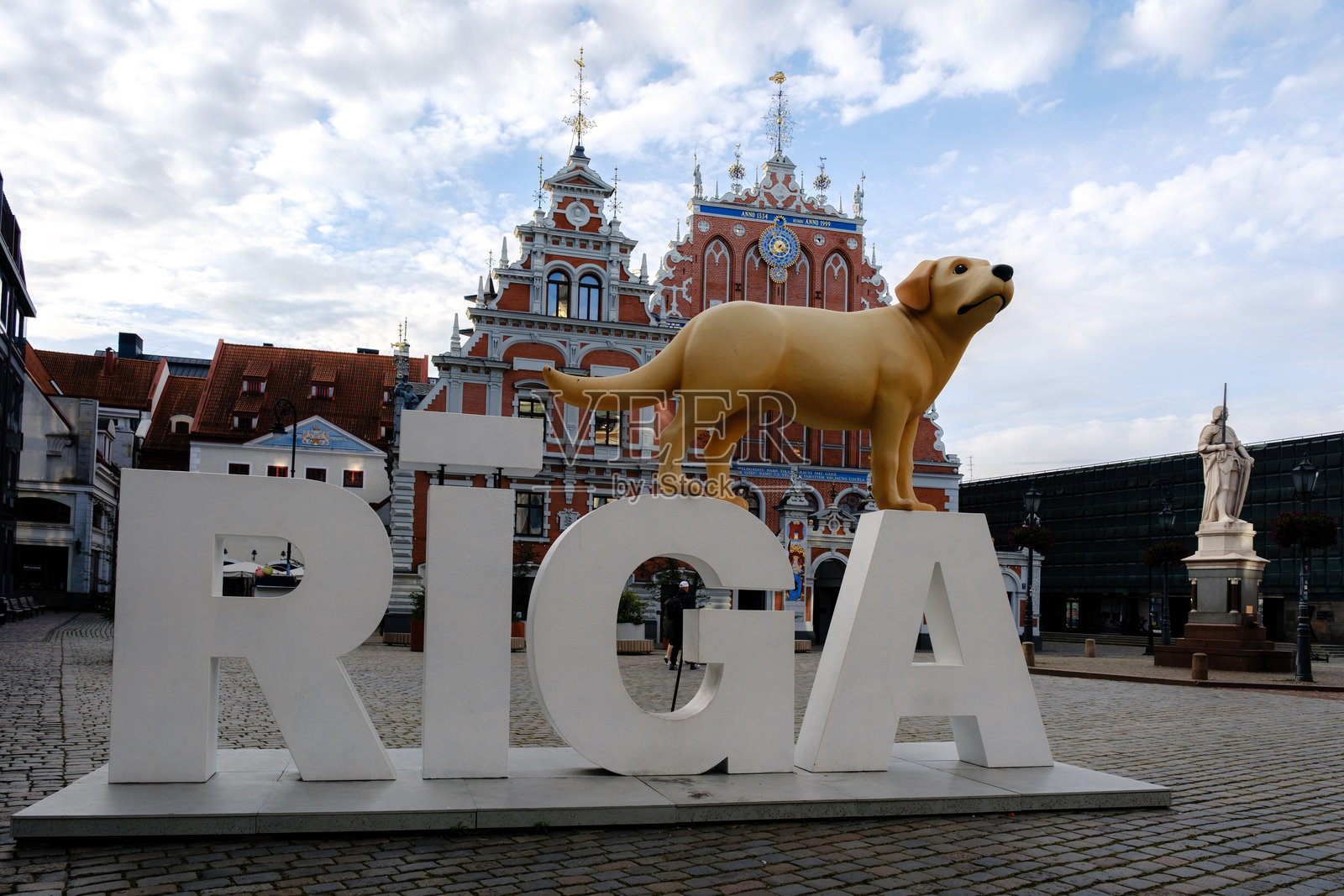 探索里加充满活力的文化，有标志性的里加标志和一个俏皮的金毛狗雕像。照片摄影图片