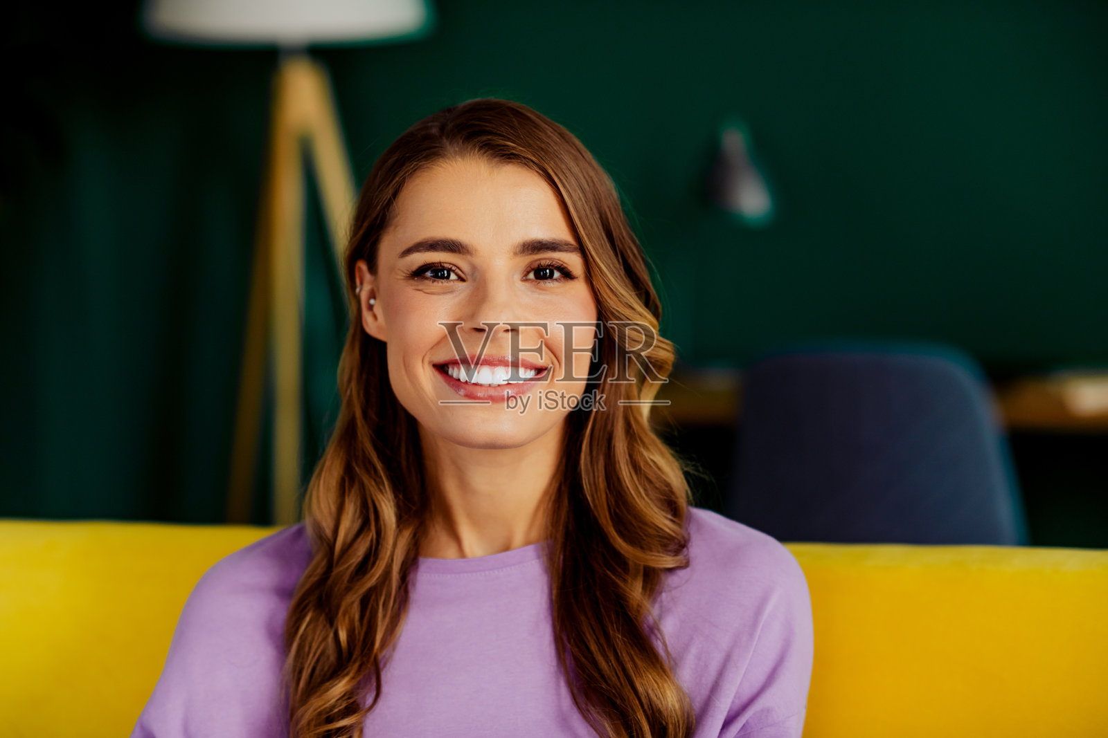 在一个色彩鲜艳、装饰明亮的室内，一位年轻女子面带微笑，在愉快的日子里拥抱温馨与放松。照片摄影图片