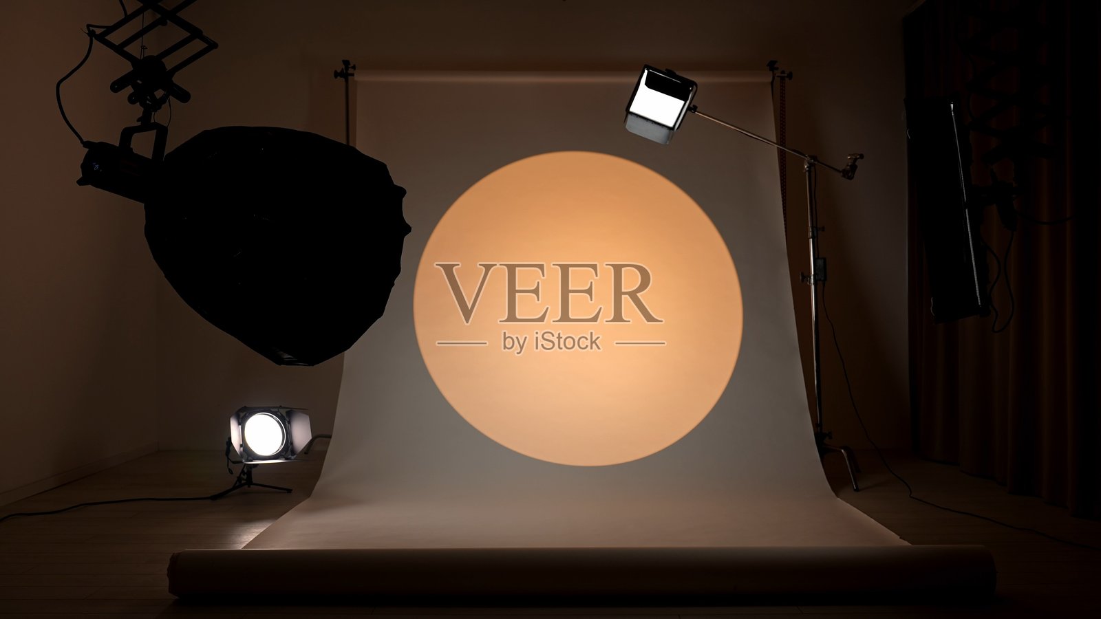 专业的影棚，配有现代照明设备、大型白色背景幕和黄色聚光灯装置，用于摄影和视频制作拍摄。照片摄影图片