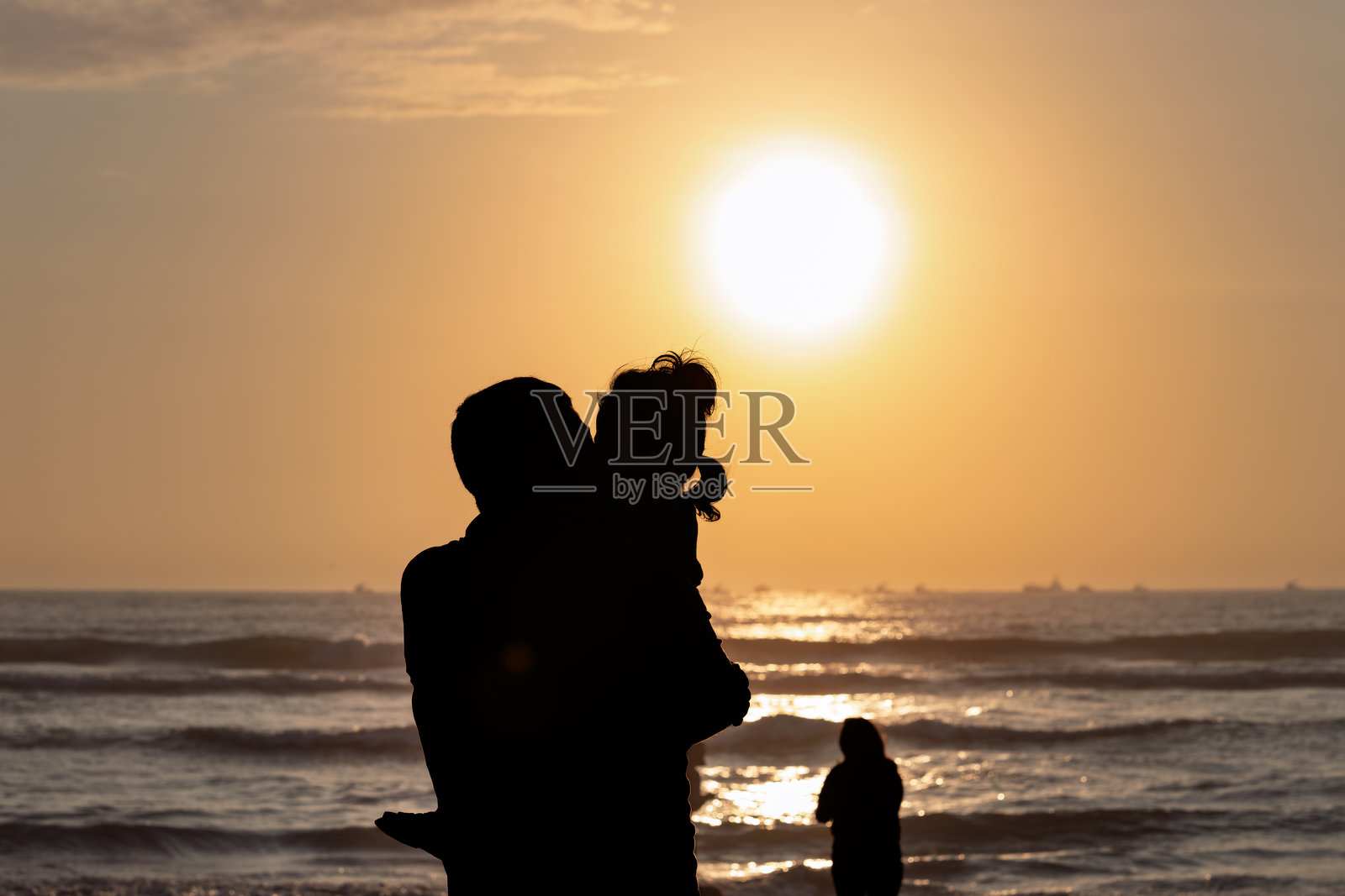 秘鲁皮门特尔海滩，父亲在日落时分怀抱女儿照片摄影图片