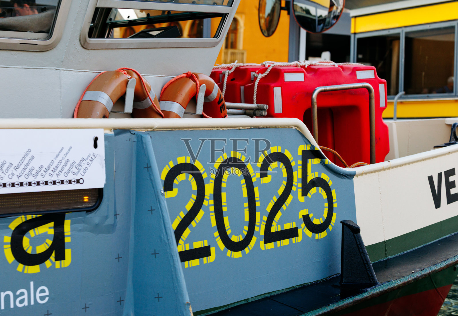 一艘色彩鲜艳的船只，上面醒目地显示着数字2025，在繁忙的港口环境中展示了充满活力的设计元素和航海设备照片摄影图片