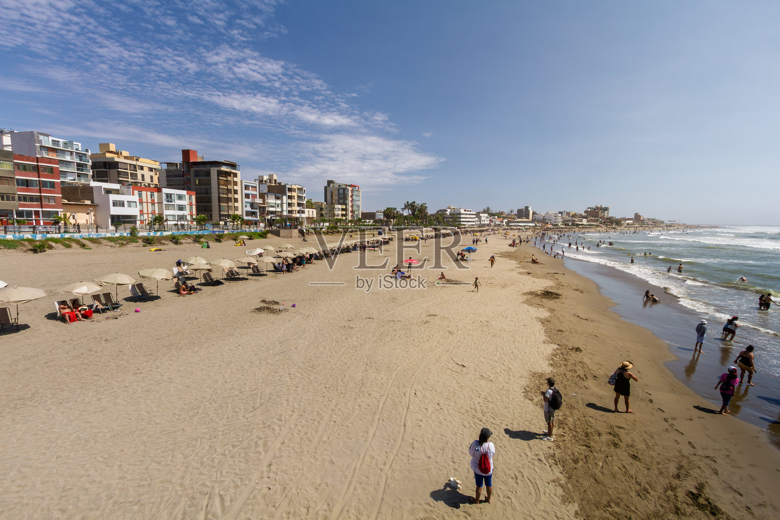 海滩全景，有建筑物、遮阳伞和享受海岸的人们照片摄影图片