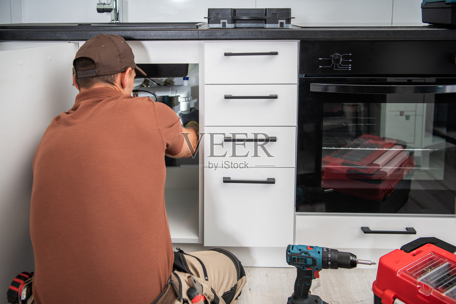 白天，技术人员在水槽下方工作，进行厨房翻新照片摄影图片