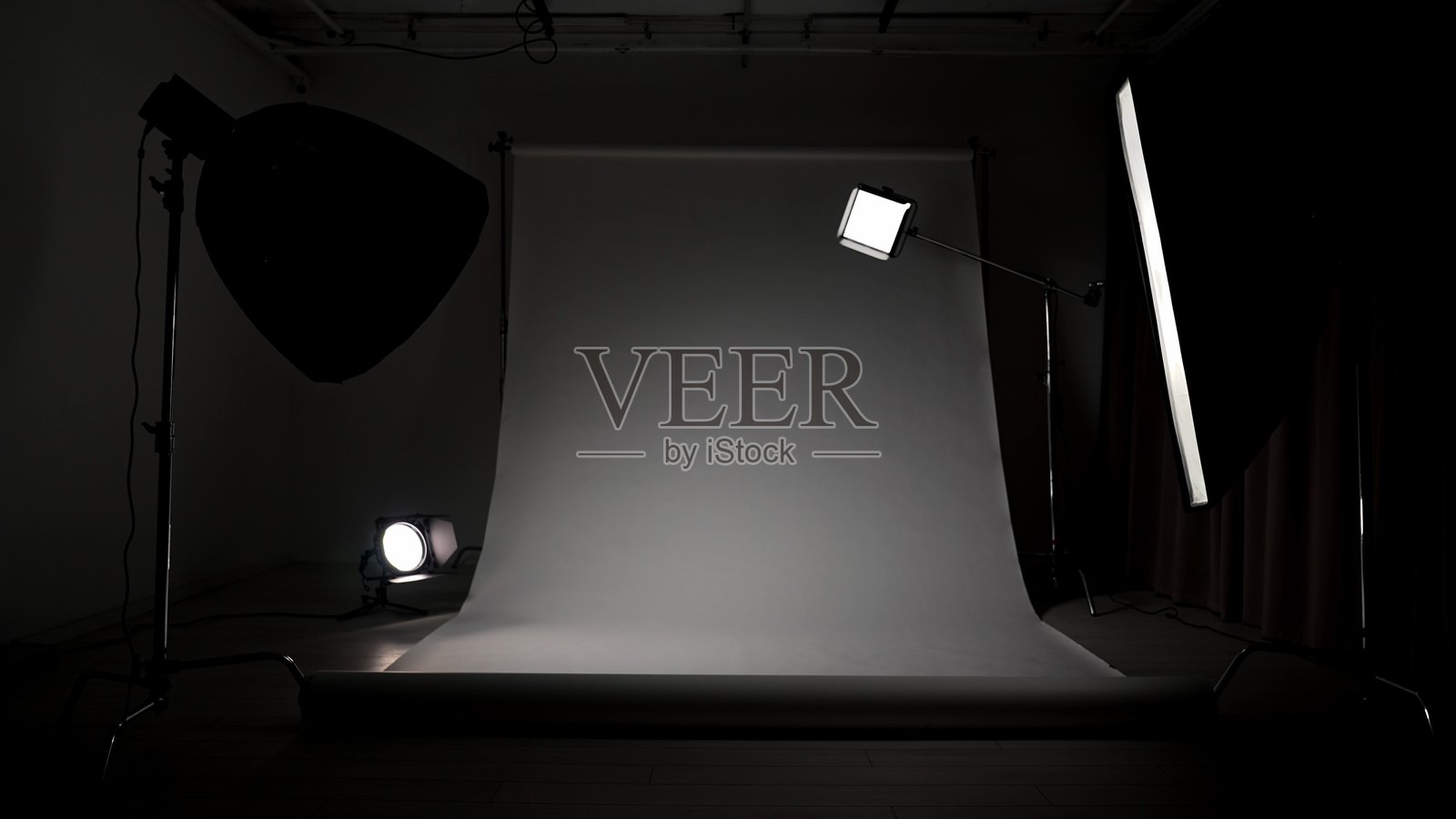 专业影棚，用于摄影和视频制作，配备现代照明设备，设有大型白色背景幕布，灯光在黑暗中设置。照片摄影图片