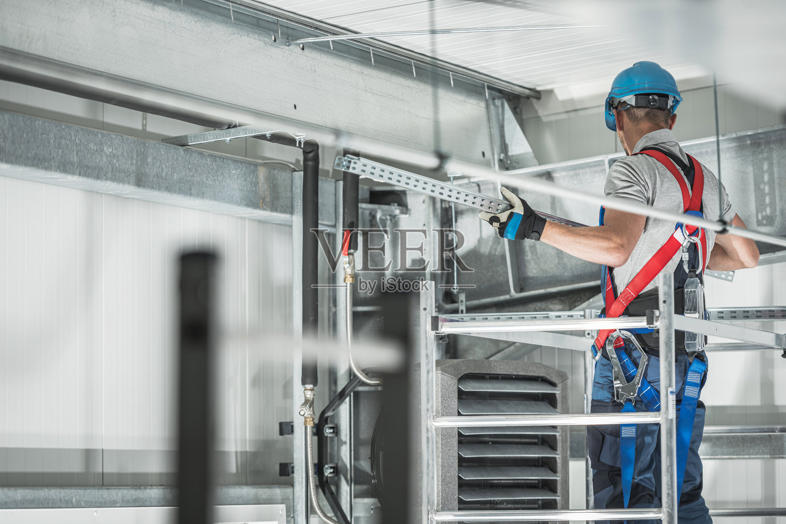 身穿防护服的工人在工业环境中安装设备，并采取了安全防护措施照片摄影图片