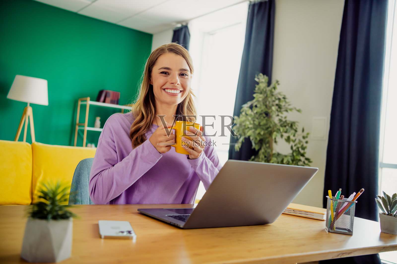 一位年轻女子在明亮现代的室内客厅里，一边喝咖啡一边远程工作，享受放松的时光照片摄影图片