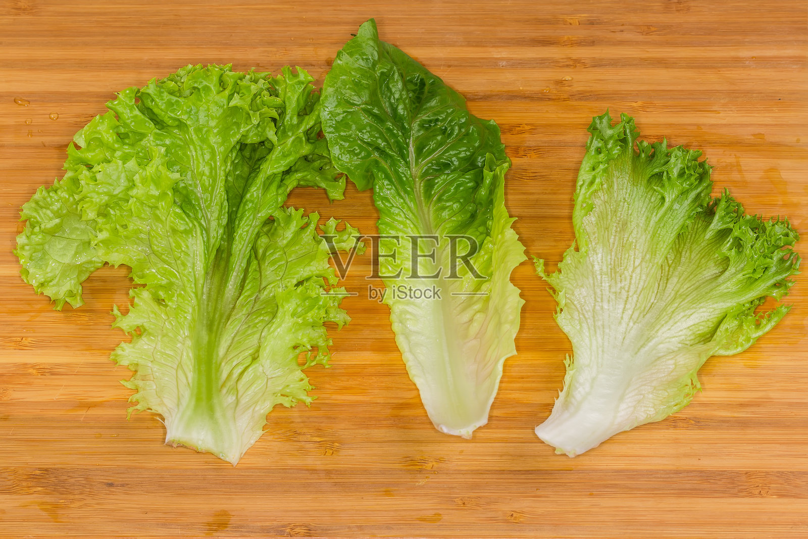 切菜板上分开的生菜叶，不同品种的绿叶生菜照片摄影图片