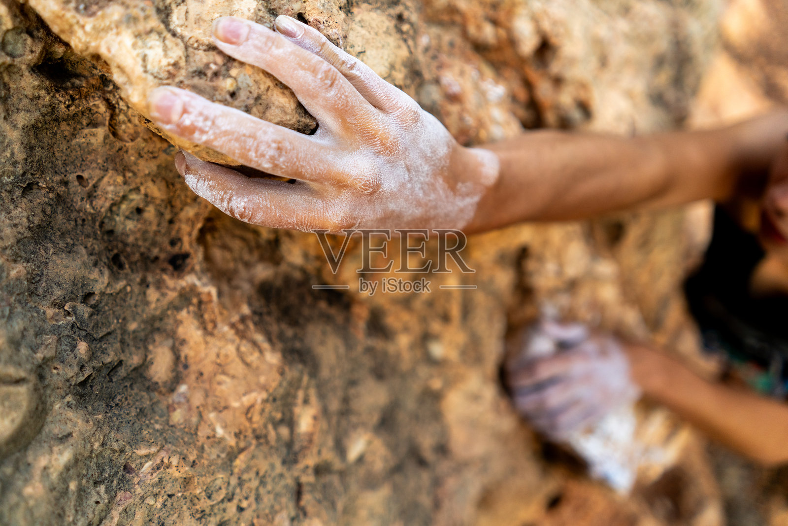 无畏地用白色镁粉攀爬岩石，手扶着岩壁边缘，获得解脱照片摄影图片