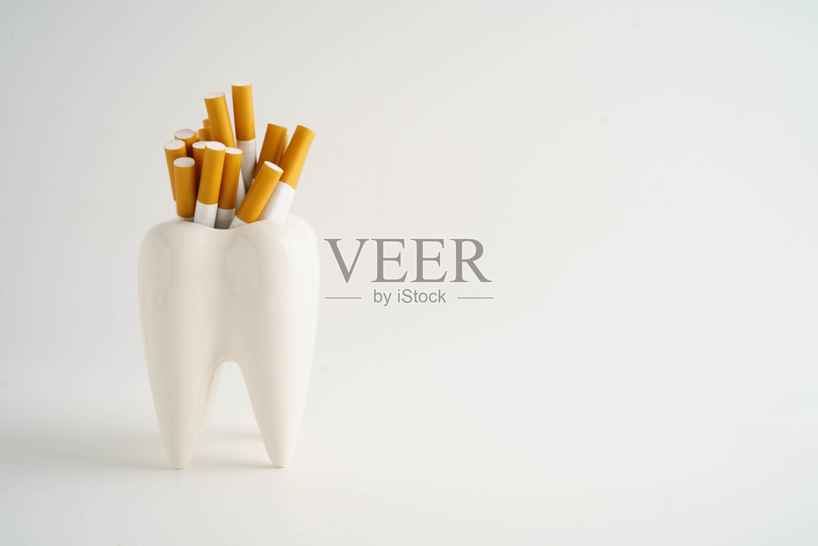 香烟与牙齿隔离在白色背景上，损害牙齿健康，禁止吸烟。照片摄影图片